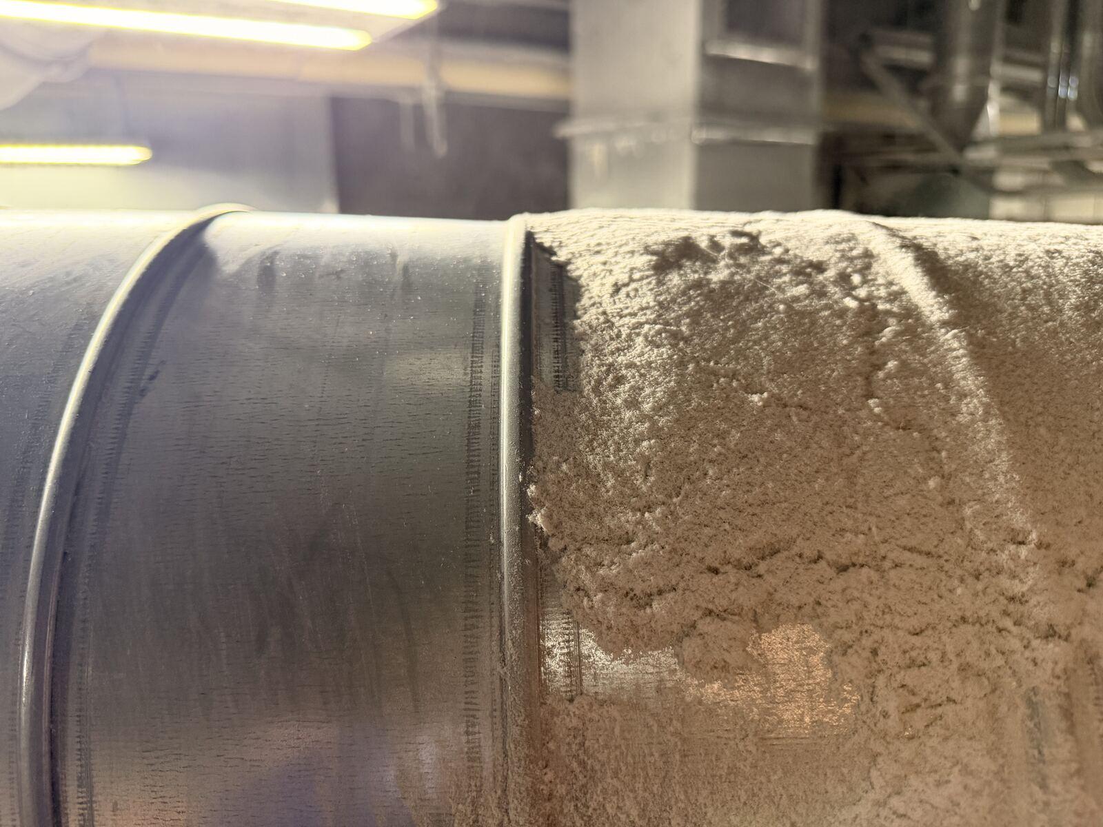 Close-up of a duct joint showing the line between cleaned and dust-covered surface